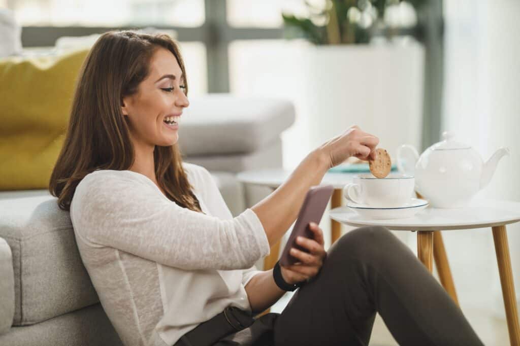 A stress-free woman in the living room having cookies and tea