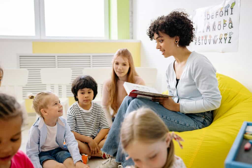 A woman is reading a book to children