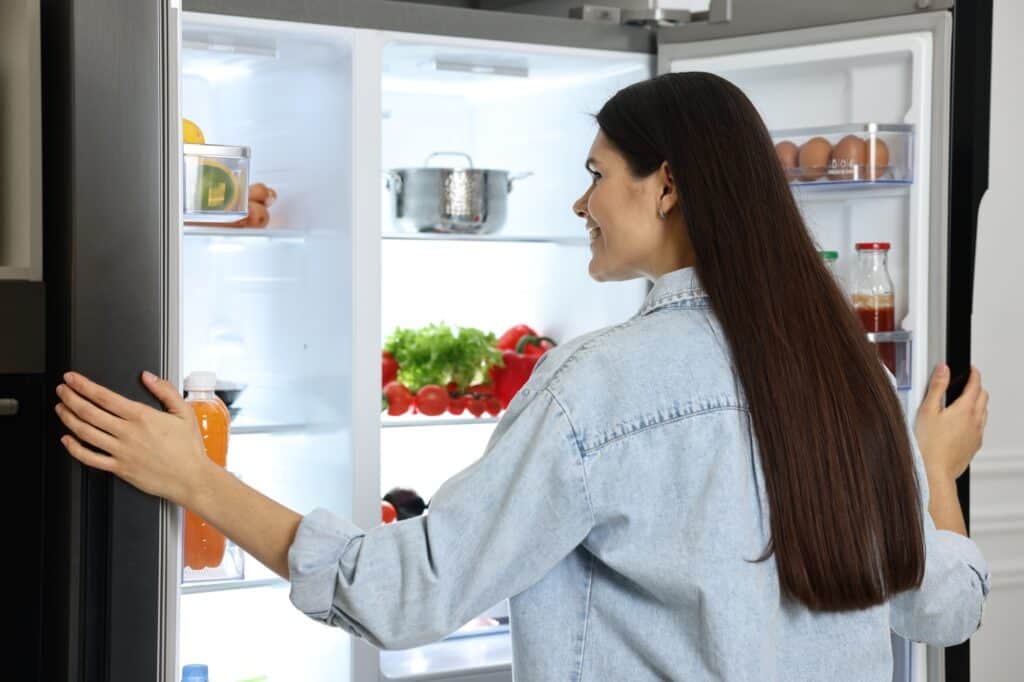 A woman in front of an open big and modern refrigerator