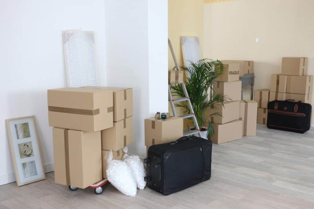 Moving boxes and pieces of luggages at the corner of the room in the concept of 'What To Do With Packing Materials After Moving House to Hounslow'.